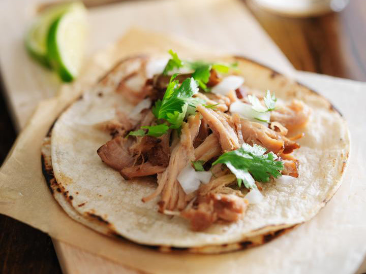 Carnitas on a grilled corn tortilla topped with cilantro and onion