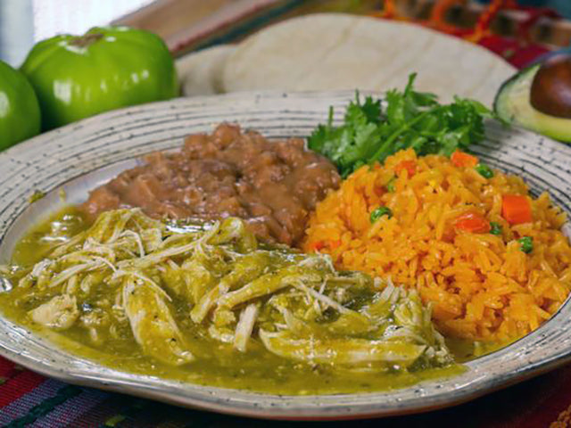 shredded chicken in roasted salsa verde on a plate with beans and rice